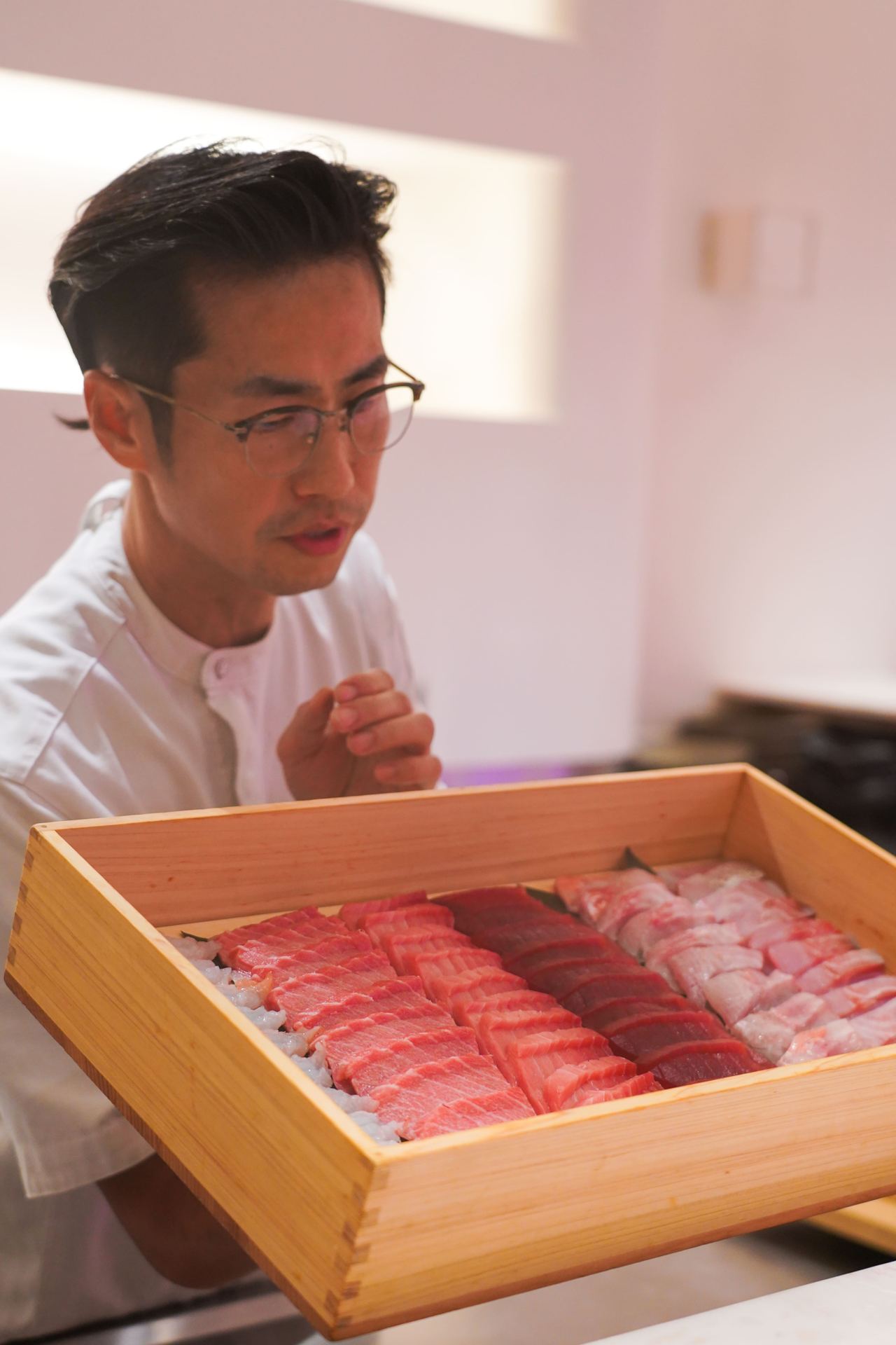 A chef with a tray of sliced tuna